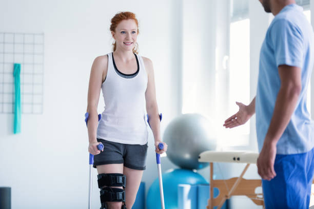 mujer caminando con muletas en fisioterapia - on one knee fotografías e imágenes de stock