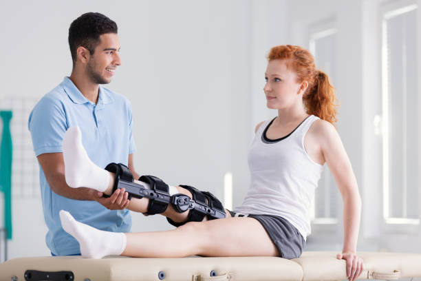 jeune femme portant un renfort au cours de la remise en état avec son physiothérapeute - ménisque photos et images de collection