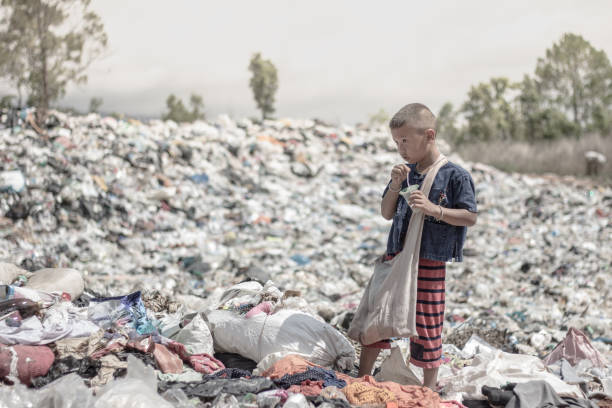 Johannesburg, Soutth Africa - December, 20th 2014: Street children seen playing at a dumpsite in Johannesburg, digging through the rubbish in hope of finding something useful. One child waves at me while others carry on in their discoveries.