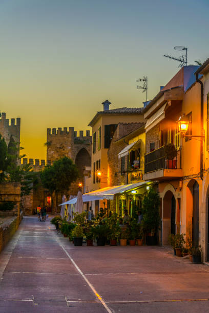 Sunset view of a narrow street in the old town of Alcudia, Mallorca, Spain Sunset view of a narrow street in the old town of Alcudia, Mallorca, Spain bay of alcudia stock pictures, royalty-free photos & images