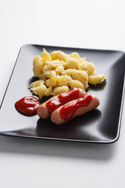 sausages with pasta and spicy sauce on a figural plate side view - fotografia de stock