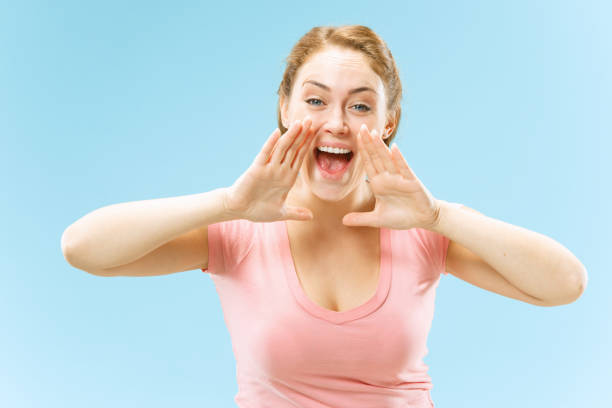 istock Isolated on blue young casual woman shouting at studio 1053436514
