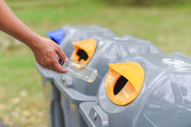 istock Close-Up Of Hand Putting Bottles In Recycling Bin 1053444640