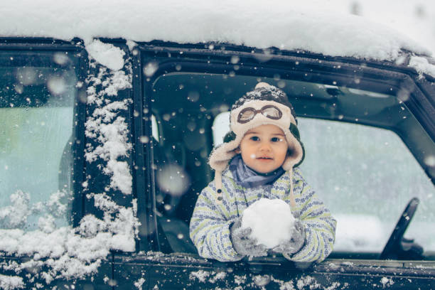 I love playing with snow Boy standing on the car window amd holding a snow nugget nub stock pictures, royalty-free photos & images