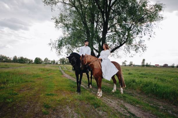 istock Couple Riding Horses On Field 1053460256