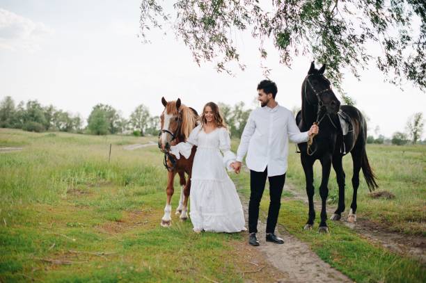 istock Couple Standing By Horses On Field 1053460284