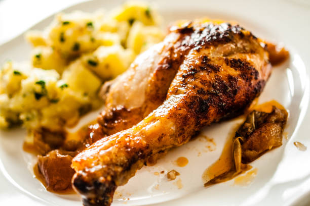 Roast chicken drumsticks with boiled potatoes on white plate