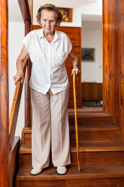 istock Elderly woman at home using a cane to get down the stairs 1053461874