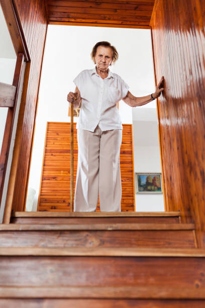 Elderly woman at home using a cane to get down the stairs