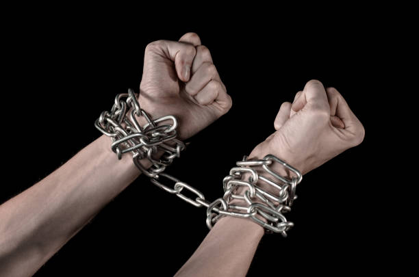 istock Hands tied chain, kidnapping, dependence, loneliness, social problem, halloween theme, killer, crazy, freedom black background 1053463832