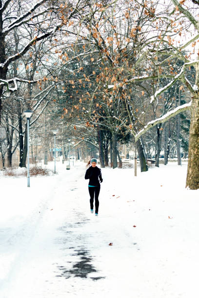 istock Woman Running On Snowy Field Against Bare Trees 1053470038