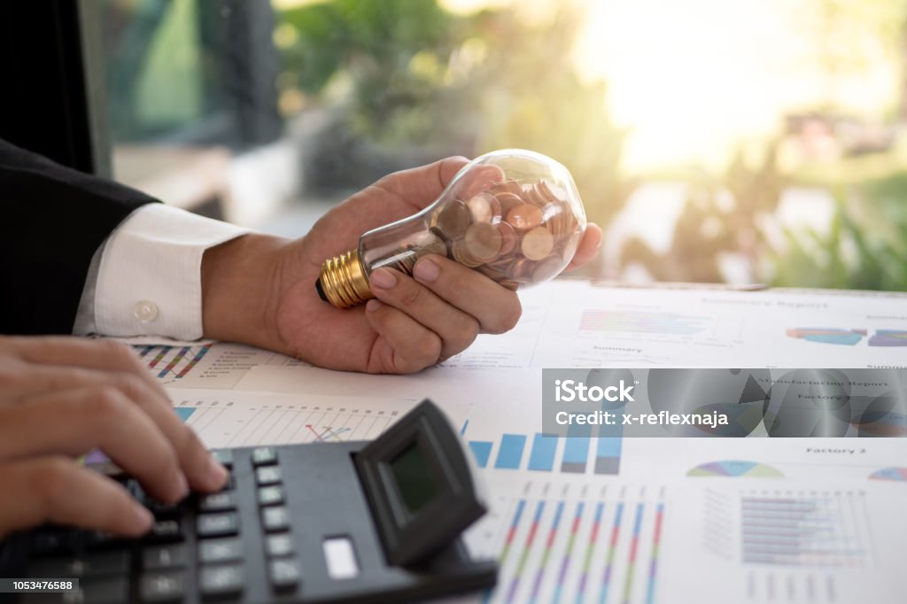 Hand of businessman hold light bulb with coin. Concept of Cost reduction and Reduce energy Vitality Stock Photo