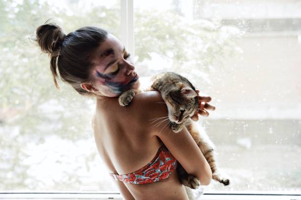 istock Woman Holding Cat Against Window At Home 1053480100