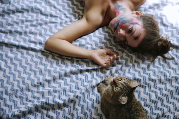 istock High Angle View Of Woman Lying With Cat On Bed 1053481316