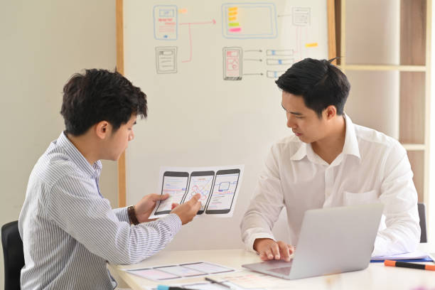 istock Two Asian Designer colleagues  drawing website UX UI app development with mockup layout mobile phone 1053482964
