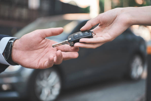 concessionnaire de voitures. jeune homme reçoit la clé de voiture de vendeuse. - contrat de bail photos et images de collection