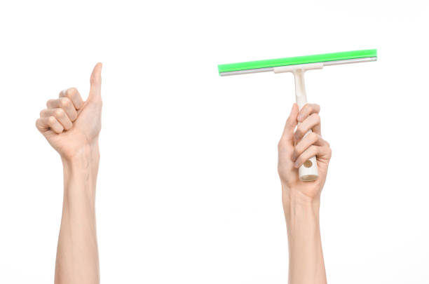 istock Household cleaning and washing windows theme: man's hand holding a green scraper windows isolated on a white background in the studio. 1053489768