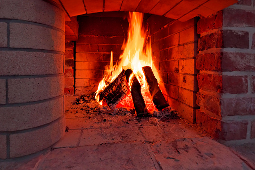 Burning logs flaming in fireplace.