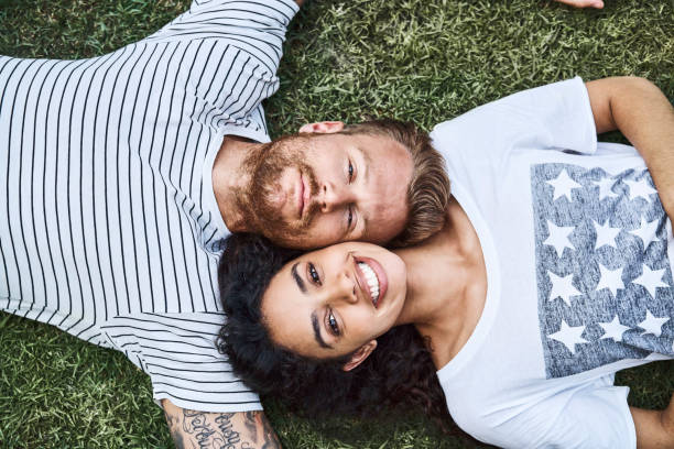 istock Multi-ethnic couple relaxing on grass at back yard 1053499272