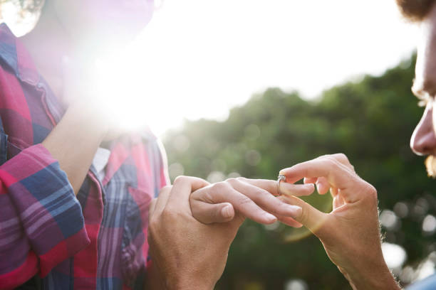 istock Back lit of man putting ring on woman's finger 1053499832