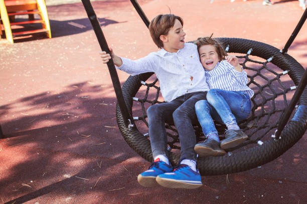 istock Brothers Swinging in Park 1053499846