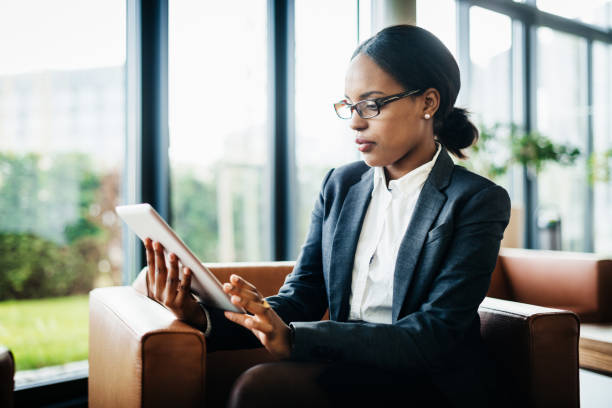 Office Employee Using Digital Tablet An office employee sitting down working, using a digital tablet. hotel reception hotel business lobby stock pictures, royalty-free photos & images