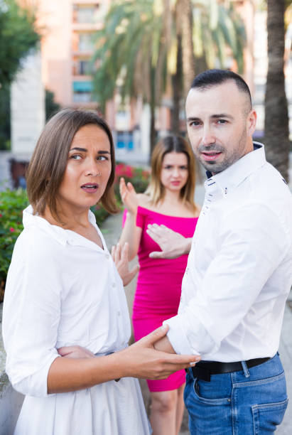 young woman is flirting with boyfriend when her girlfriend is envying them - disaffection imagens e fotografias de stock