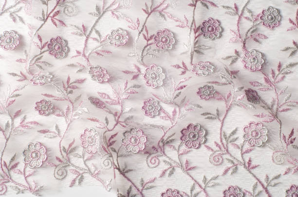istock Texture, background, pattern. Pink lace decorated with flowers on a white background. Background of pink lace fabric beautifully decorated with flowers 1053513860