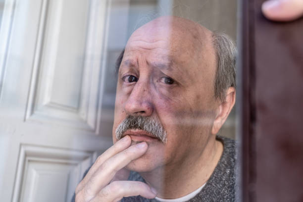istock Old senior man looking throughout the window feeling confused and depressed alone at home in Aging Retirement Widower Dementia and Alzheimer concept. 1053516056
