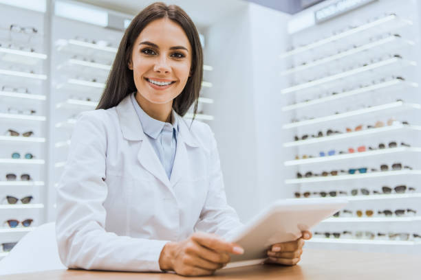 istock beautiful smiling oculist using digital tablet in ophthalmic shop 1053516084