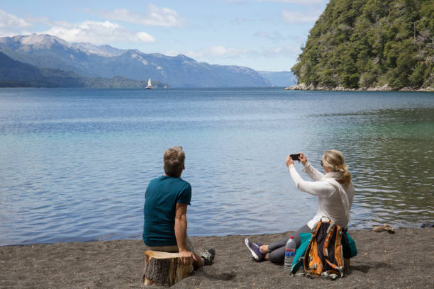 Mature couple take photo on beach by mountain lake Mature couple take photo on beach by mountain lake nahuel huapi national park stock pictures, royalty-free photos & images