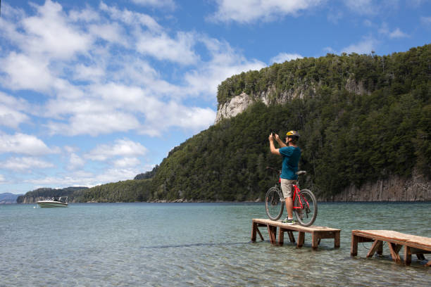 male Bicyclist dock mountain lake Bicyclist pauses on small dock on mountain lake nahuel huapi national park stock pictures, royalty-free photos & images