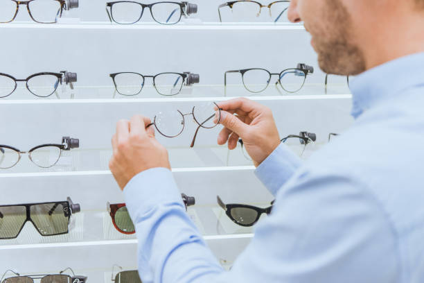 istock partial view of man taking eyeglasses from shelves in optics 1053517150