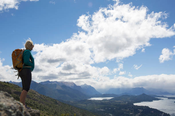 Hiker pauses on bluff above lakes and mountains