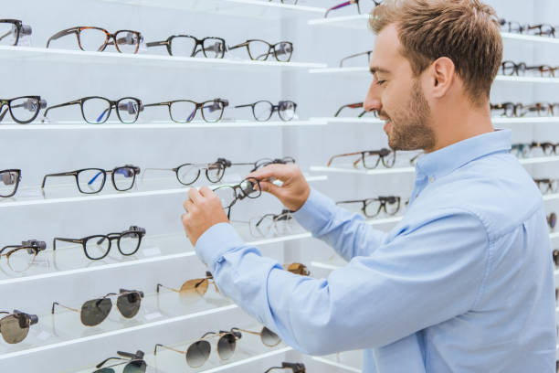 istock side view of smiling young man taking eyeglasses from shelves in optics 1053517302