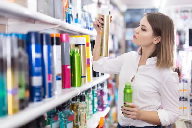 Young concentrated woman looking for haircare cosmetics in shop