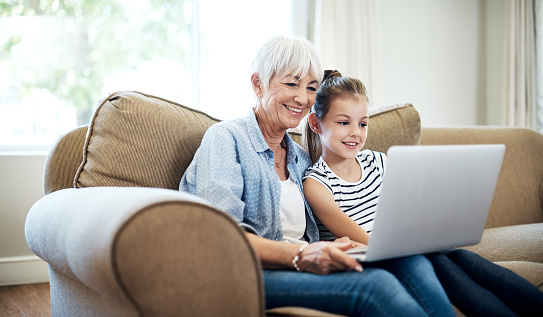 Shot of an adorable little girl using a laptop with her grandmother at home
