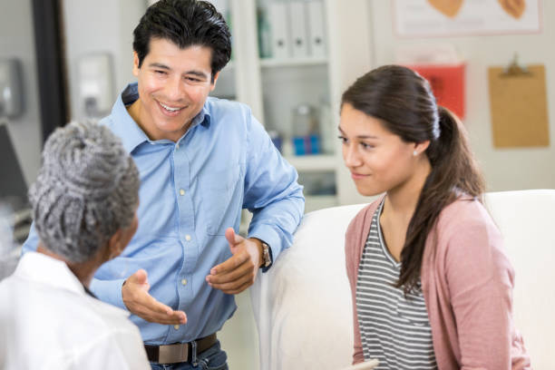 istock Mid adult father talks with his daughter's doctor 1053526776