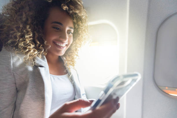 istock Excited young woman texts on airplane 1053526800