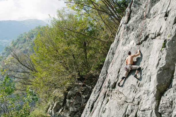 istock Man climbing a rock wall in safety 1053533938