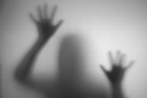 Shadow of man on the white frosted glass representing dangerous, fear, help, haunting, horror and scary.