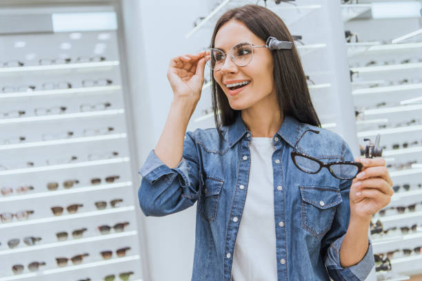 istock smiling attractive woman choosing eyeglasses in optics 1053540616