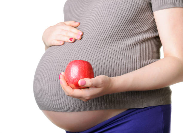 istock Pregnant woman holding a red apple 1053542270