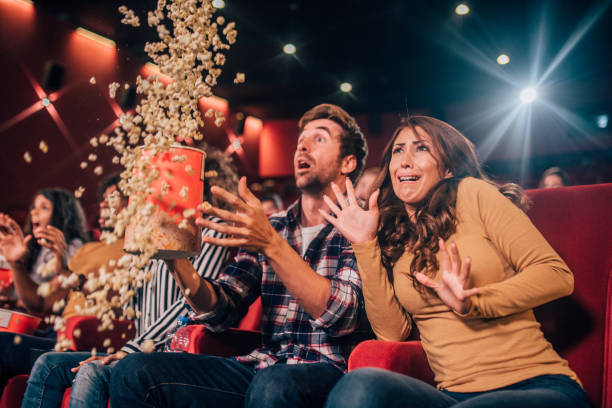 istock Scared friends spilling popcorn at cinema 1053542594