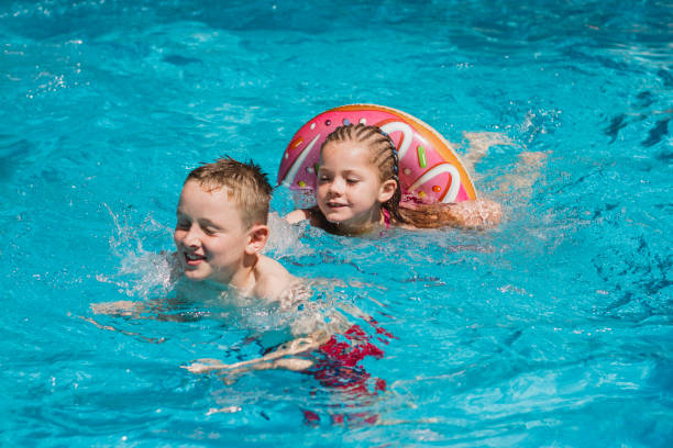 двое детей наслаждаются бассейном - water sport family inner tube sport стоковые фото и изображения