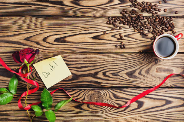 inschrift auf dem papier neben rote rose mit band und eine tasse kaffee in der nähe von kaffeebohnen auf alten holztisch tun. draufsicht mit textfreiraum. sankt valentin-tag-konzept - coffee bean coffee flower ribbon stock-fotos und bilder