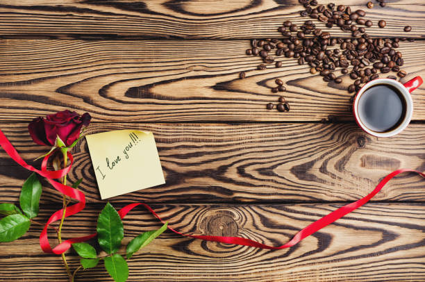 inscripción te quiero en papel al lado de rosa roja con cinta y taza de café junto a granos de café en la mesa de madera vieja. vista superior con espacio de copia. concepto de día de san valentín - coffee bean coffee flower ribbon fotografías e imágenes de stock