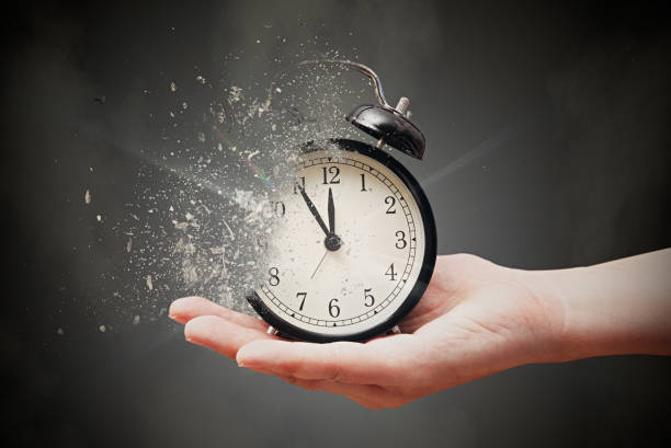Concept of passing away, the clock breaks down into pieces Concept of passing away, the clock breaks down into pieces. Hand holding analog clock with dispersion effect clock face photos stock pictures, royalty-free photos & images