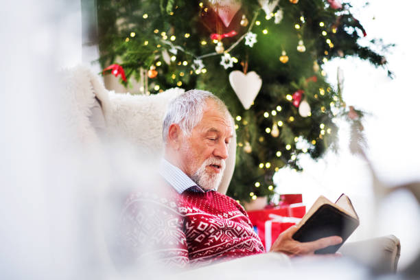 istock A senior man reading a book at home at Christmas time. 1053560206