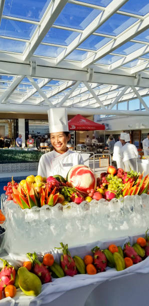 Happy server shows this colorful poolside brunch fruit on a cruise ship. Surprise brunch served on Viking Sky as we traveled to our new port. A North Sea cruise, we spent the day aboard the ship. This colorful ice sculpture display of colorful fruit was was one food station of many wonderful, tasty, food offerings.